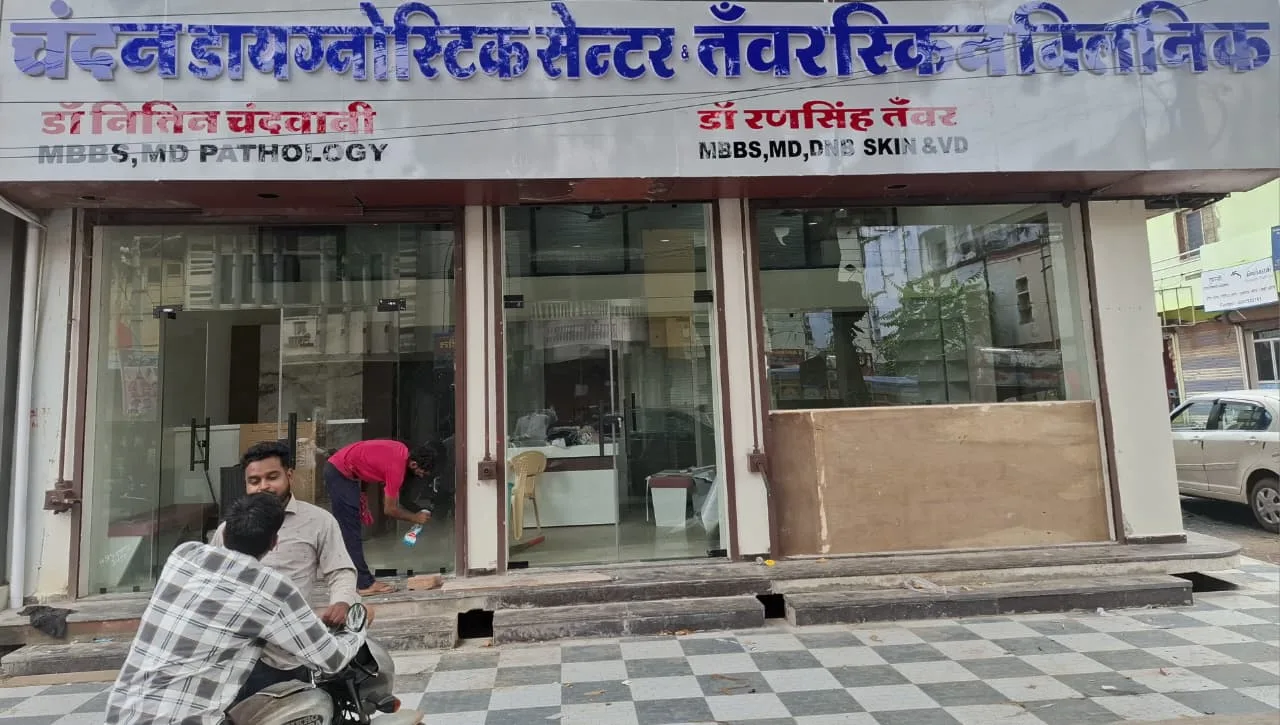 Exterior storefront view of Tanwar Skin Clinic and Chandan Diagnostic Center featuring doctor qualification signboards.